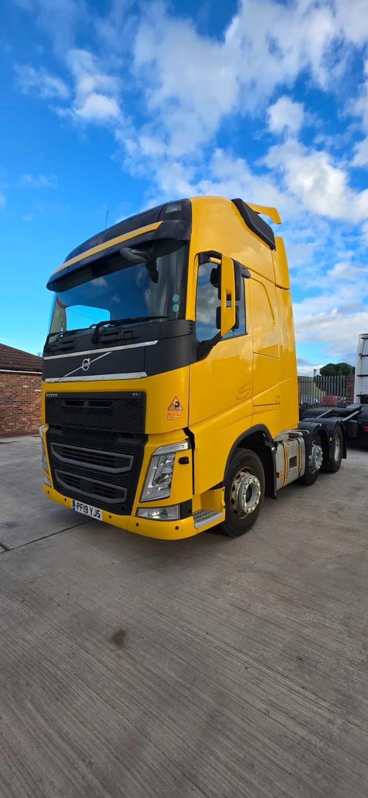 Yellow Volvo tractor unit parked beneath a blue sky